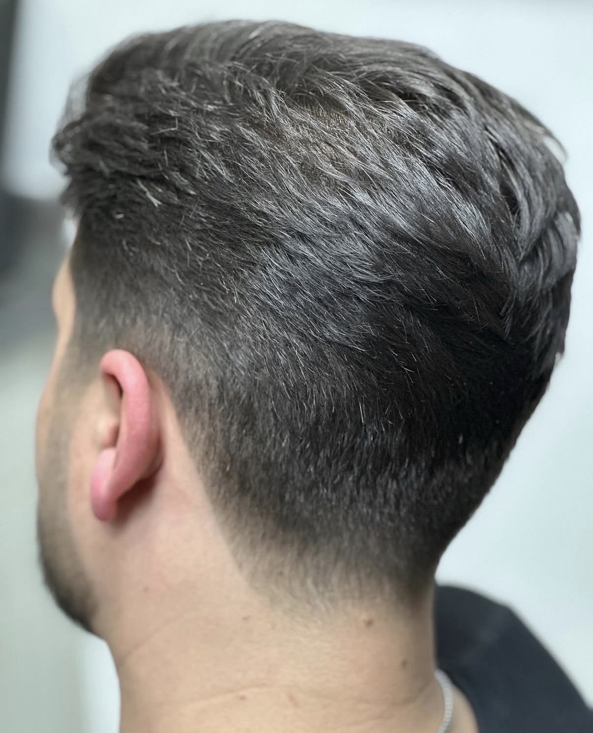 Low taper fade blended into thick dark hair
