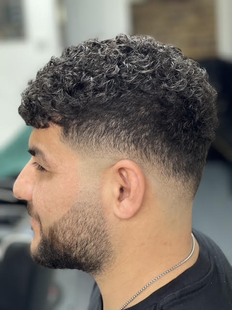 Curly top with a mid taper and lined beard