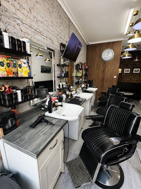 Inside the shop — barber chairs, brick wall and slatted timber